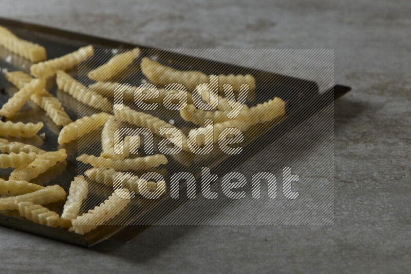 crinkle fries in a black stainless steel rectangle tray on grey textured counter top