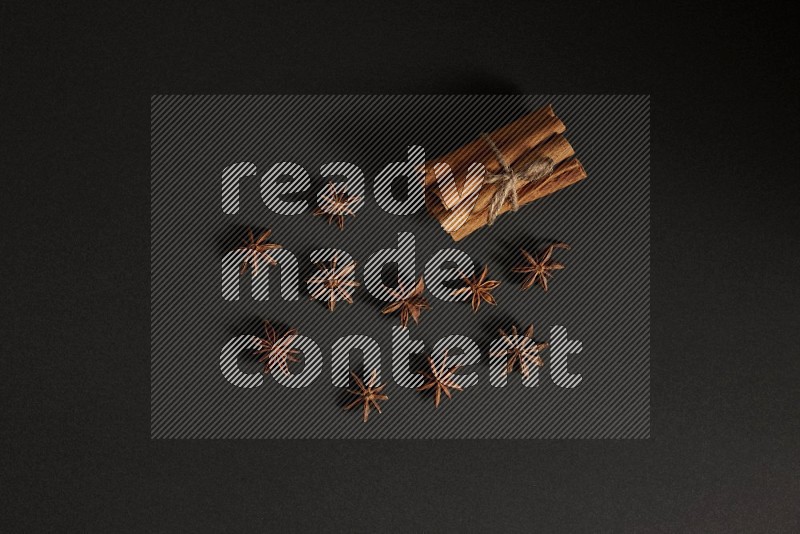 Cinnamon sticks stacked and bounded and star anise on black background