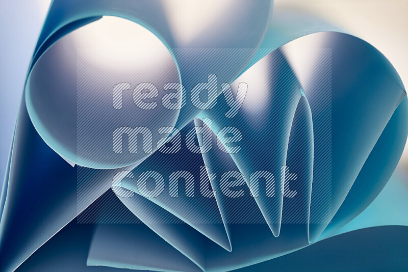 An artistic display of paper folds creating a harmonious blend of geometric shapes, highlighted by soft lighting in blue tones