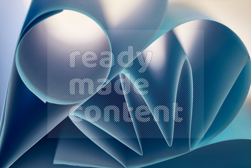 An artistic display of paper folds creating a harmonious blend of geometric shapes, highlighted by soft lighting in blue tones