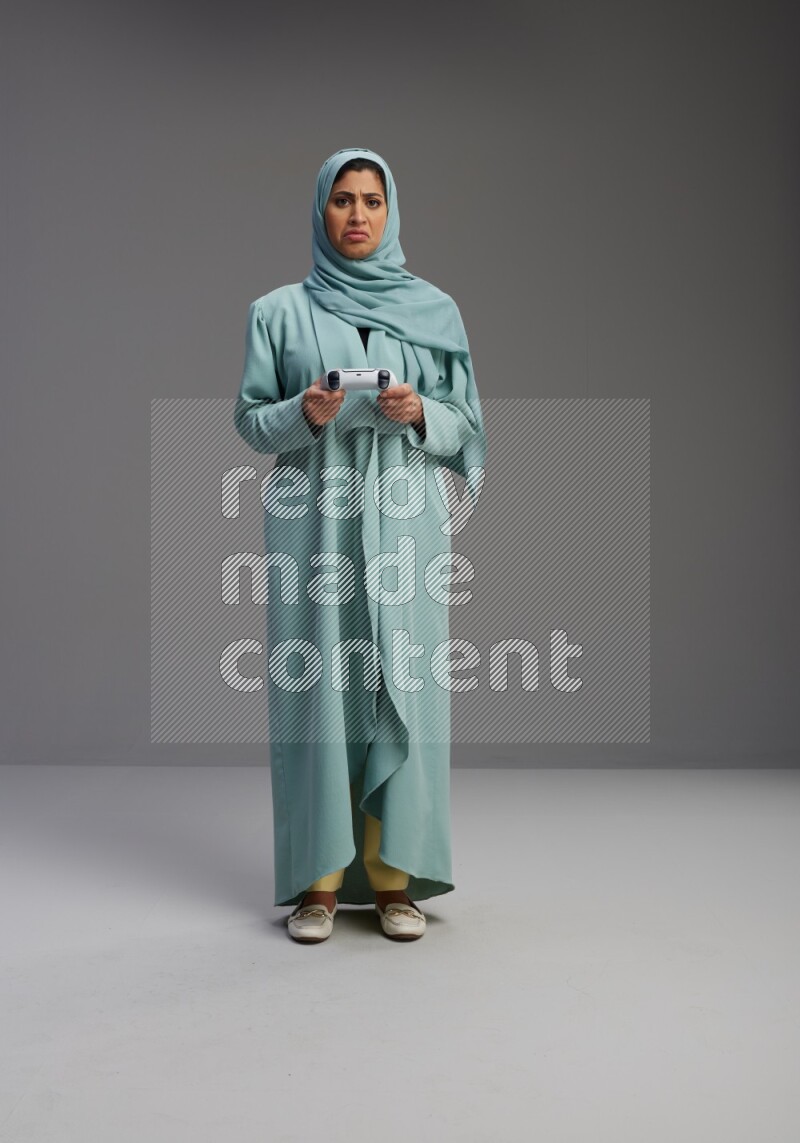Saudi Woman wearing Abaya standing Playing Games on Gray background