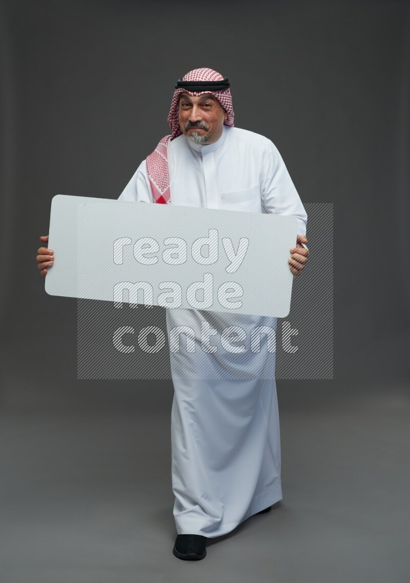 Saudi man with shomag Standing holding social media sing on gray background