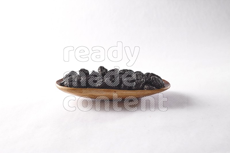 Dried plums in a wooden plate on white background