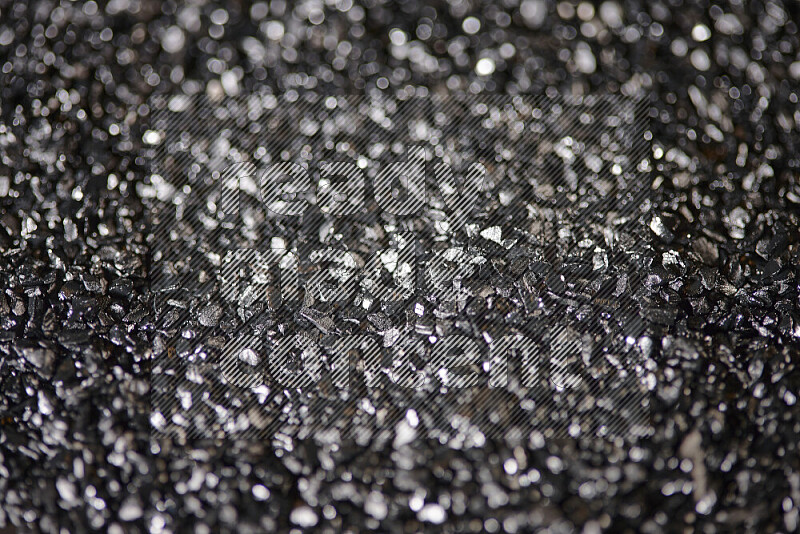 Black shimmering fragments of glass scattered on a black background