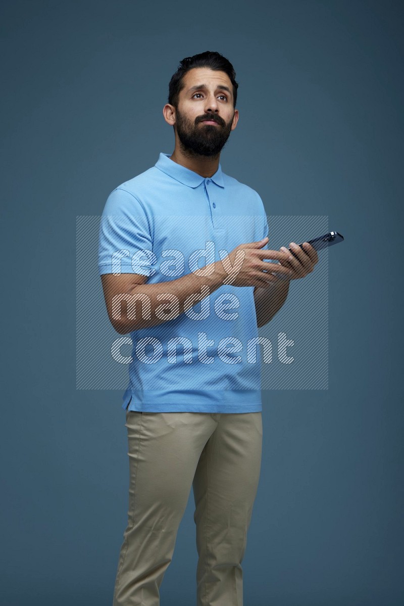 Man posing with a phone in a blue background wearing a Blue shirt
