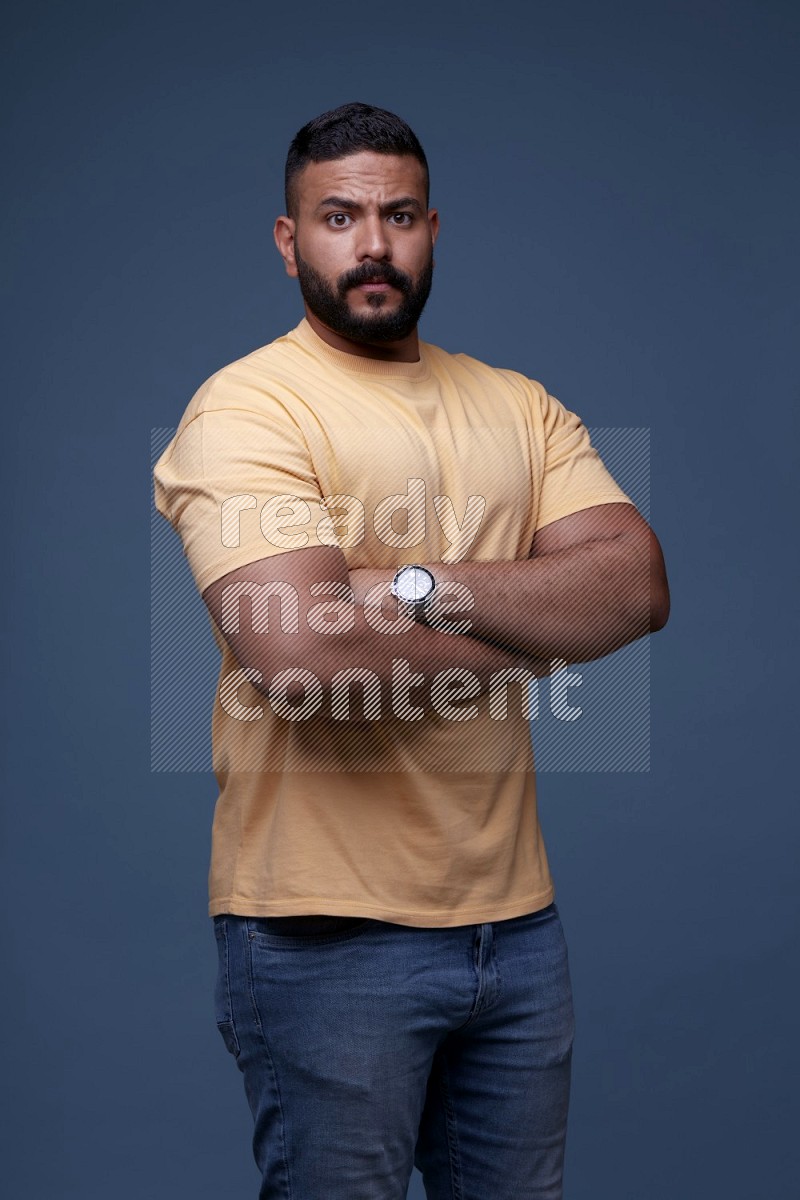 A man posing in a blue background wearing a yellow shirt