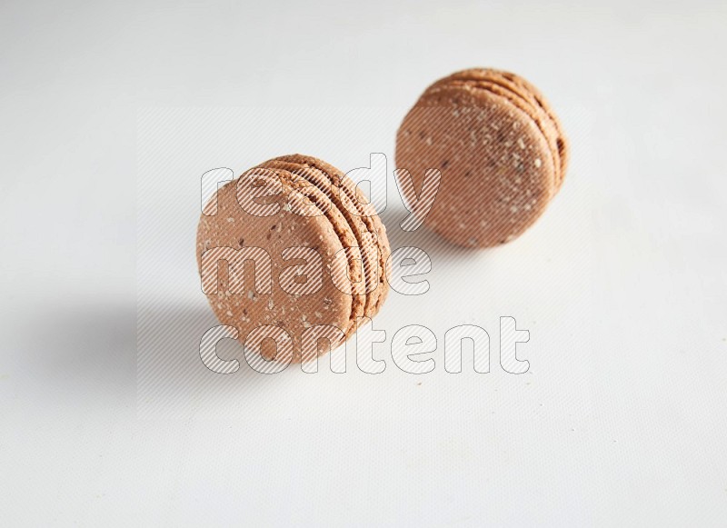 45º Shot of two Brown Hazelnuts macarons on white background