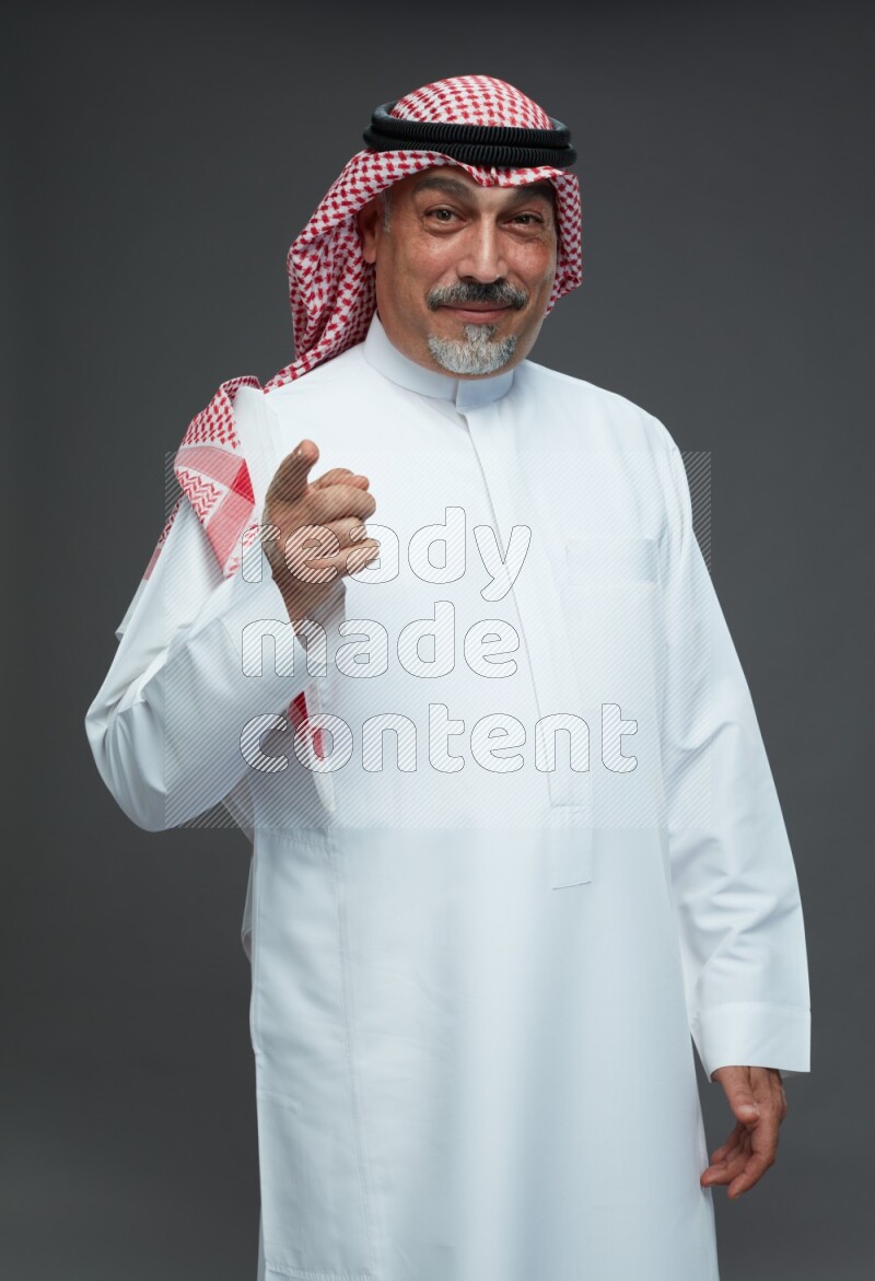 Saudi man with shomag Standing Interacting with the camera on gray background