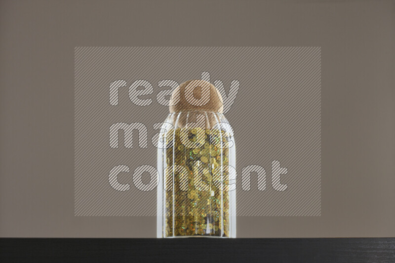 Sequins in a glass jar on black background