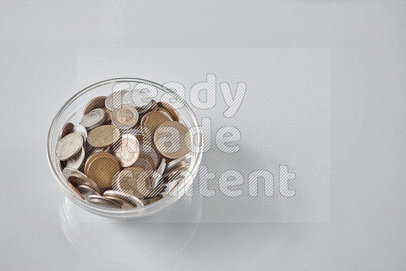 Random old coins in a glass bowl on grey background