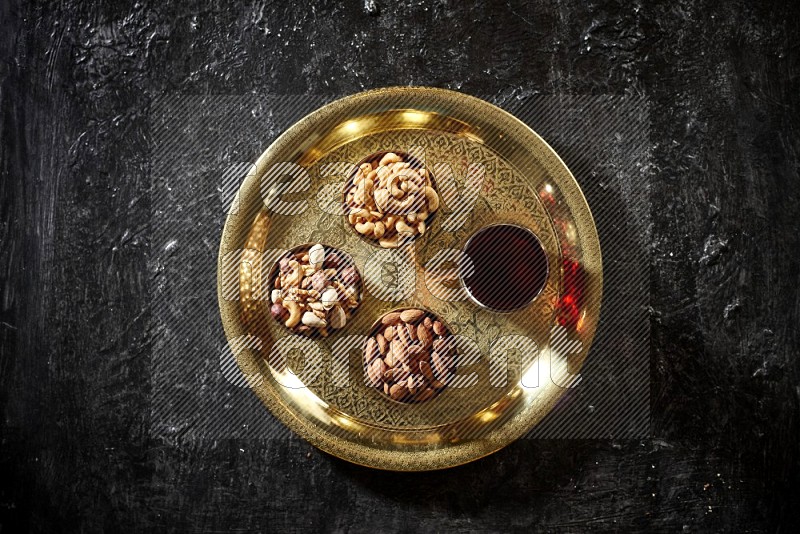 Nuts in metal bowls with Hibiscus on a tray in dark setup