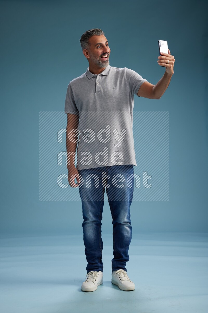 Man Standing taking selfie on blue background