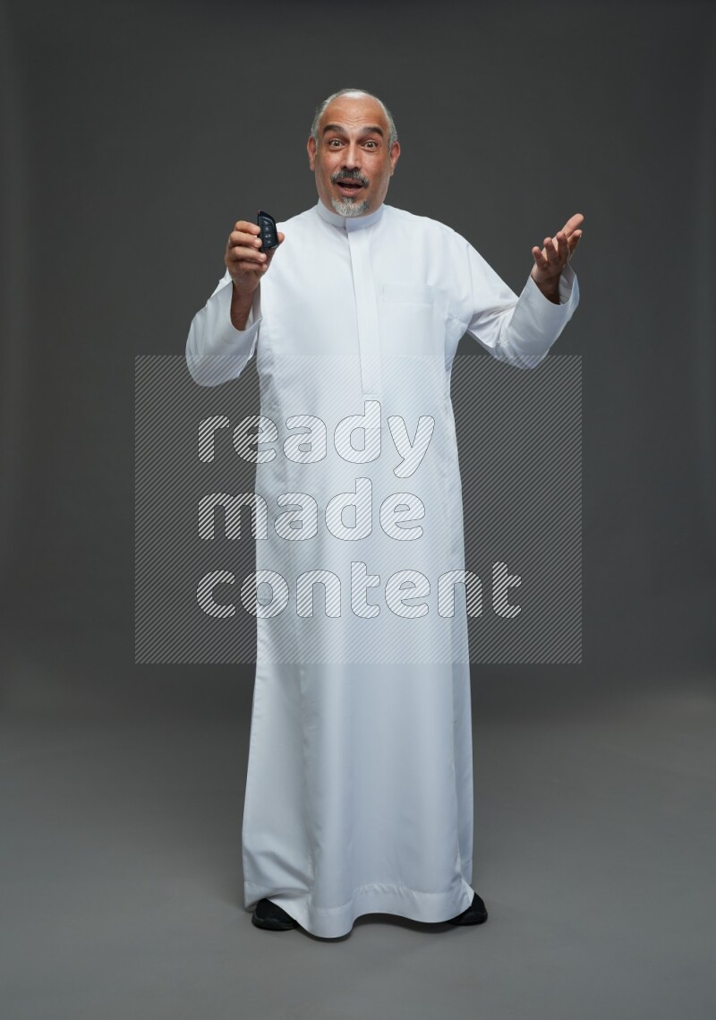 Saudi man without shomag Standing holding car key on gray background