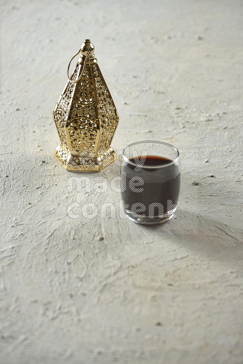 A golden lantern with drinks, dates, nuts, prayer beads and quran on textured white background