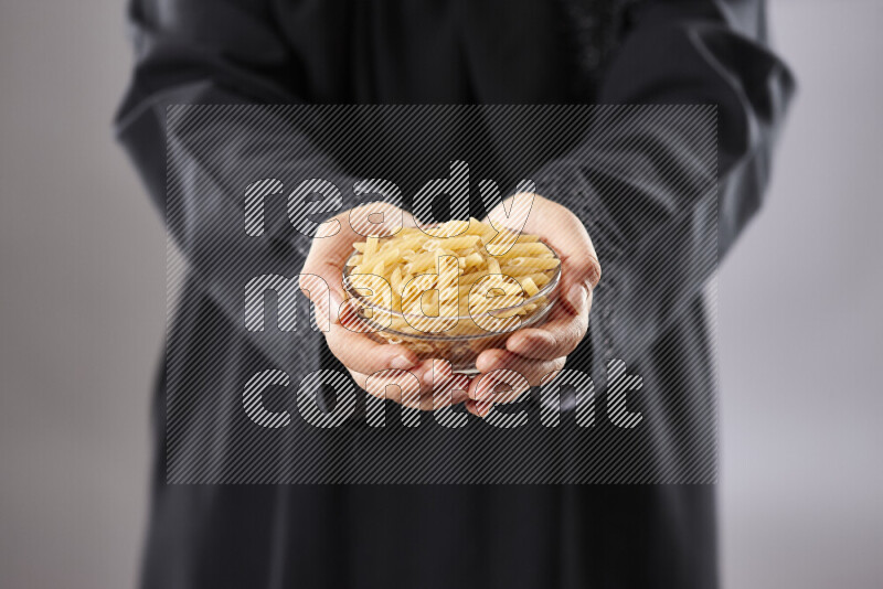 Woman in abaya holding different kinds of pasta in different positions