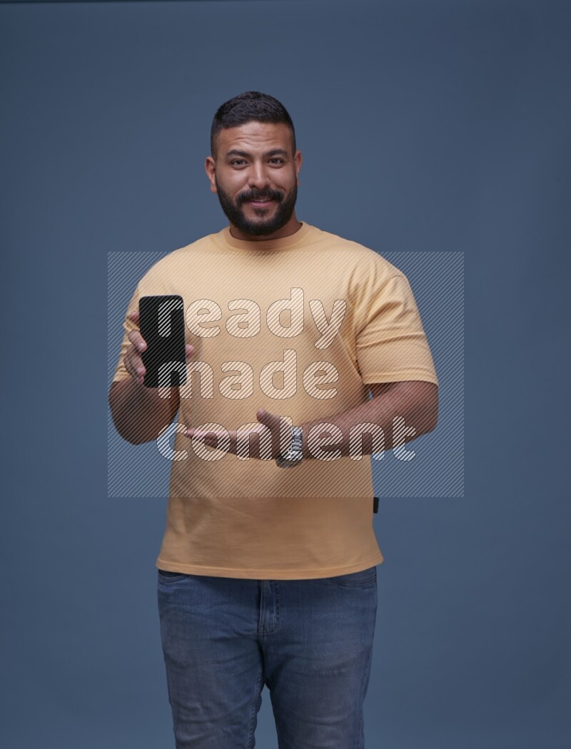A man Showing His Smart Phone on Blue Background wearing Orange T-shirt