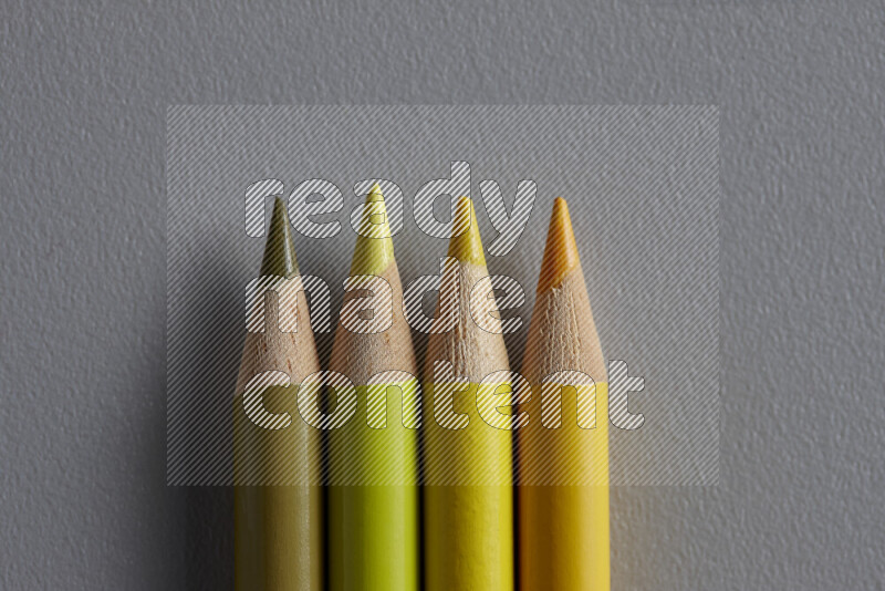 مجموعة من أقلام الرصاص الملونة مرتبة لتعرض تدرجا من الألوان الصفراء علي خلفية رمادية