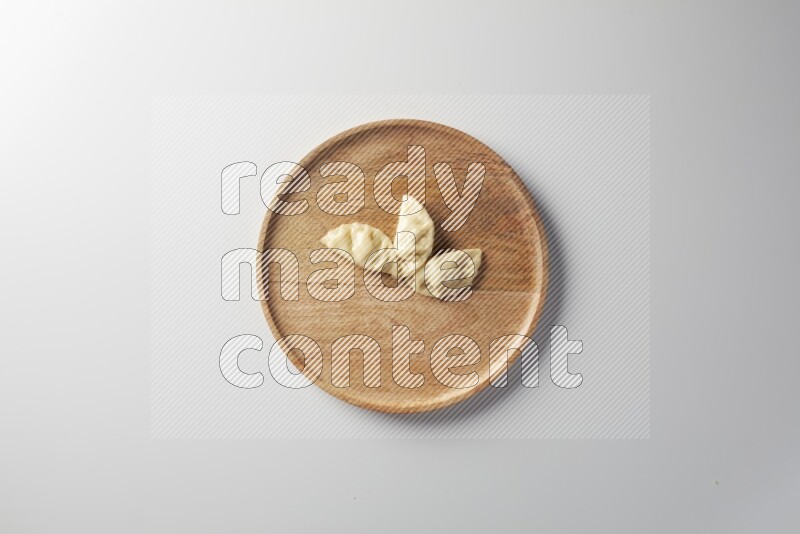 Three Sambosas on a wooden round plate on a white background