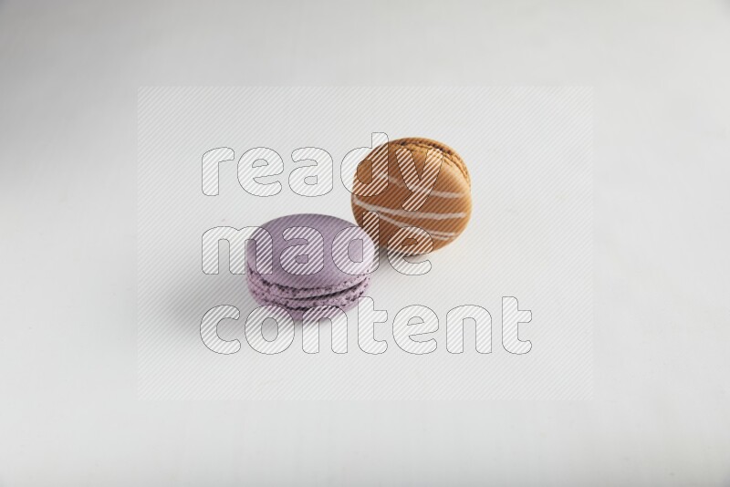 45º Shot of of two assorted Brown Irish Cream, and Purple Blueberry macarons on white background