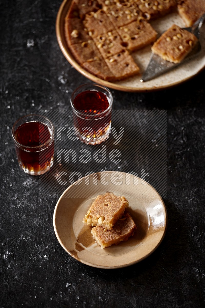 Basbousa with tea in a dark setup