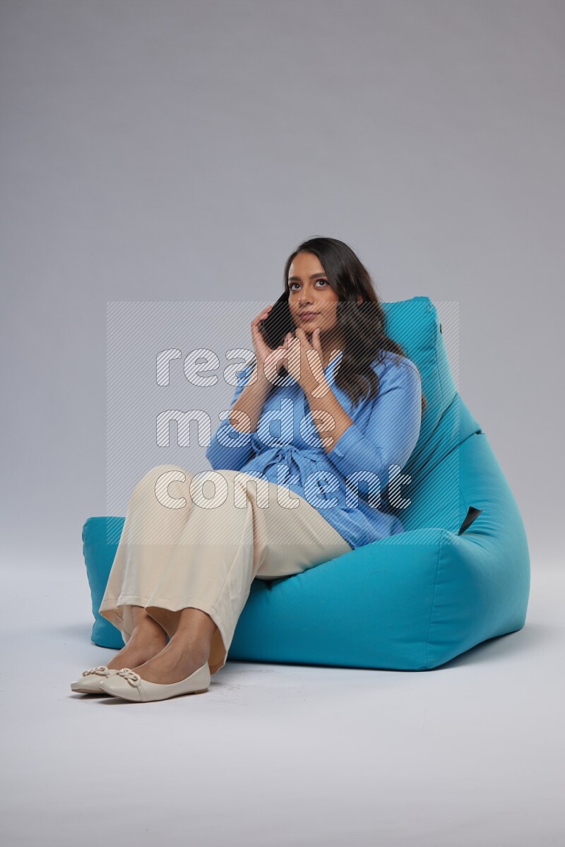 A woman sitting on a blue beanbag and talking on the phone