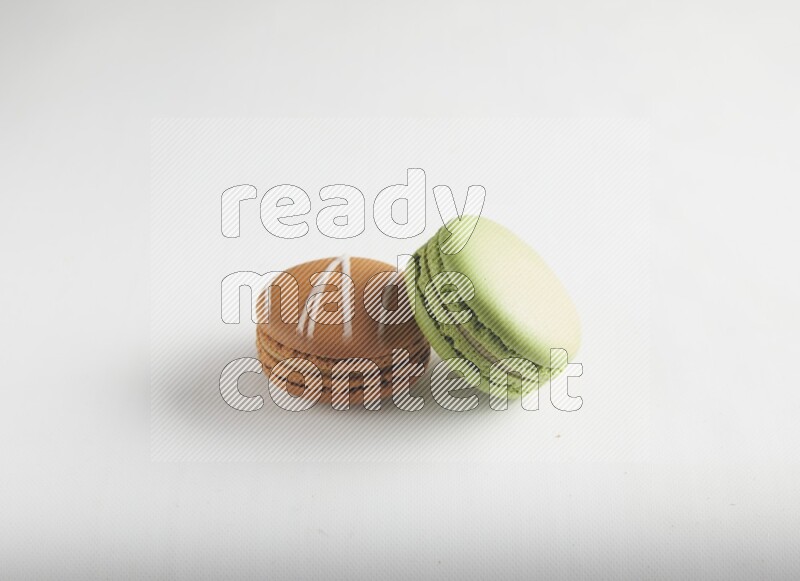 45º Shot of of two assorted Brown Irish Cream, and Green Pistachio macarons on white background