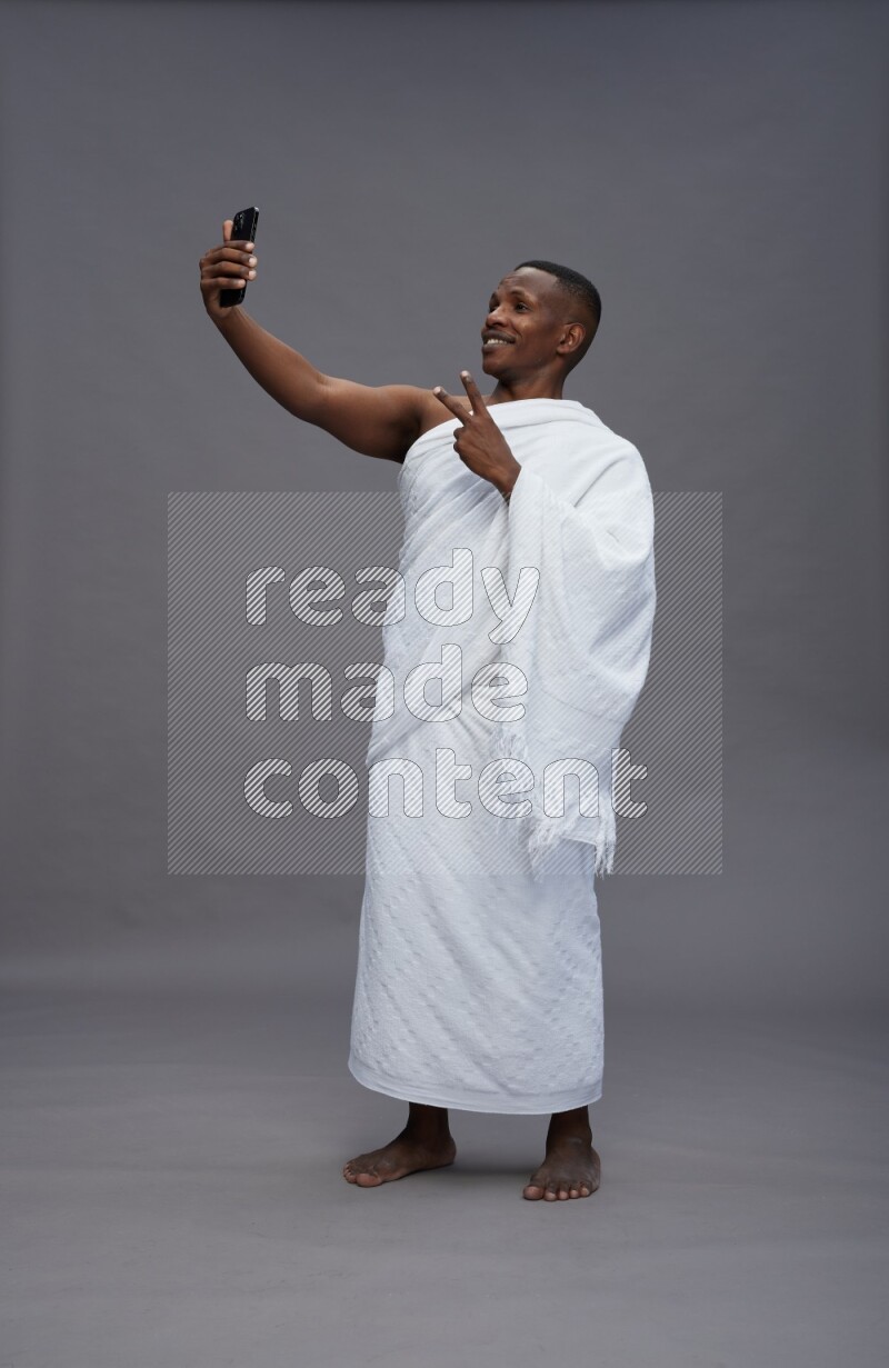 A man wearing Ehram Standing taking selfie on gray background