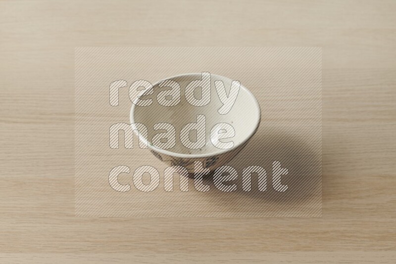 A decorative pottery bowl on light wooden background