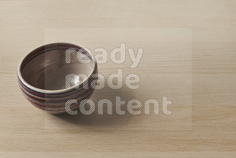 A multicolored pottery bowl on light wooden background