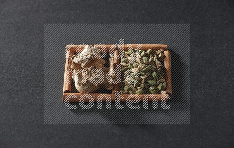 2 squares of cinnamon sticks full of cardamom and dried ginger on black flooring