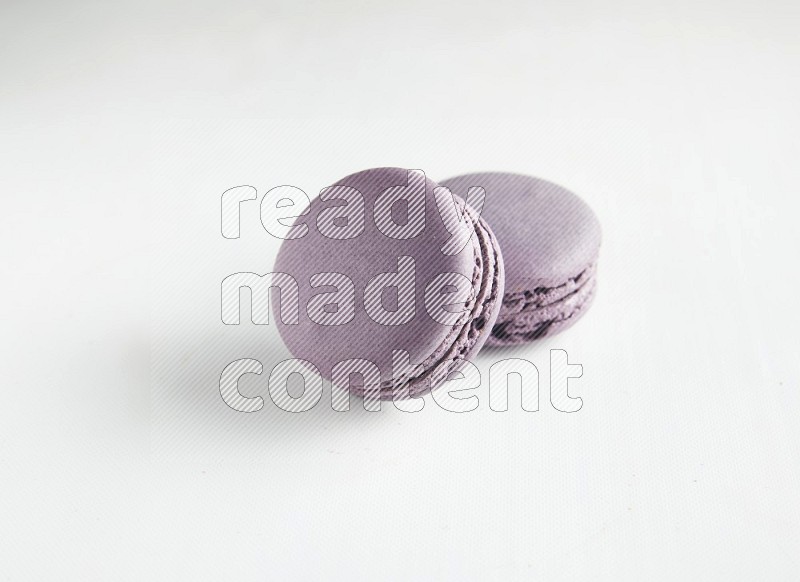 45º Shot of two Purple Blueberry macarons on white background