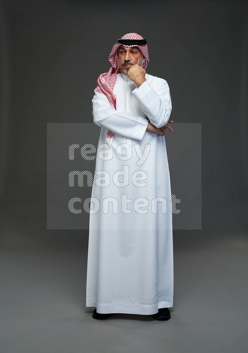 Saudi man with shomag Standing Interacting with the camera on gray background