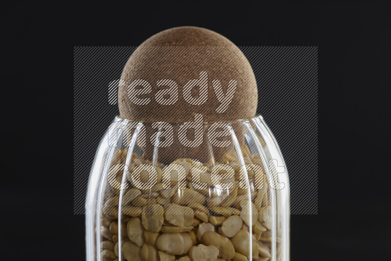 Crushed beans in a glass jar on black background