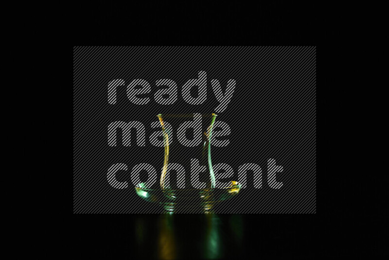 Glassware with rim light in green and yellow against black background