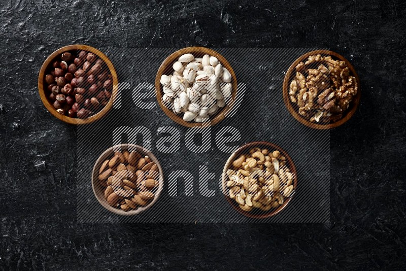 Nuts in wooden bowls in a dark setup