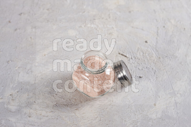 A glass jar full of fine himalayan salt on white background