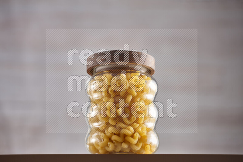 Raw pasta in glass jars on beige background