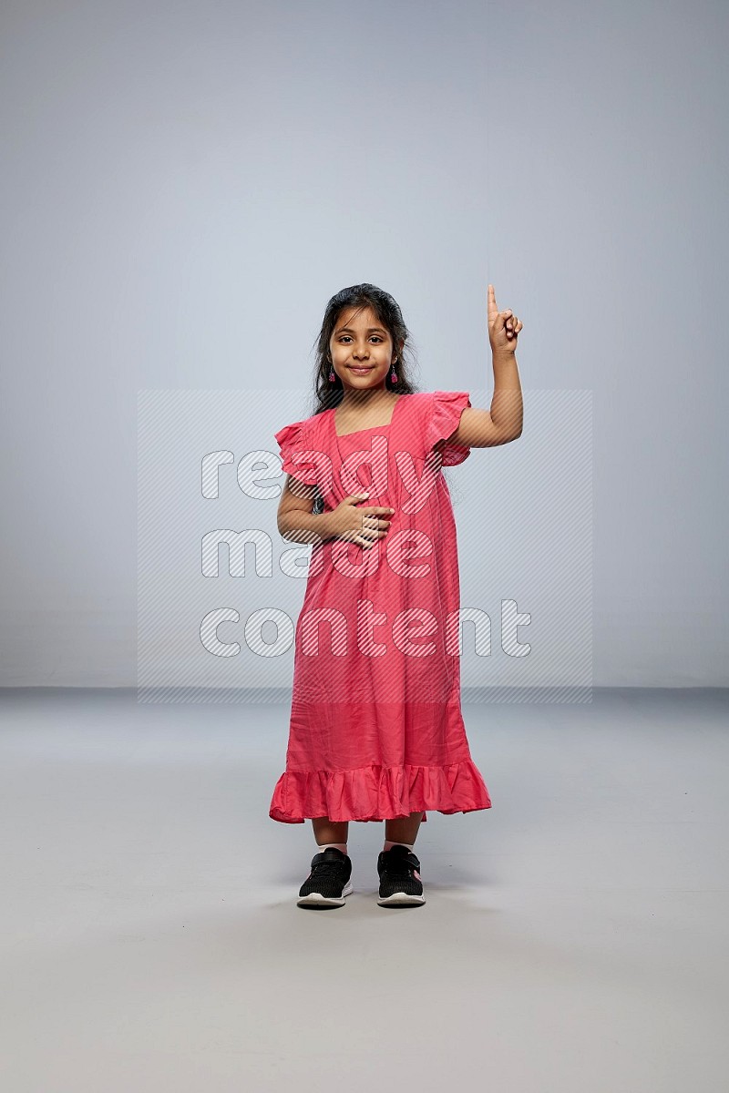 A girl standing interacting with the camera on gray background