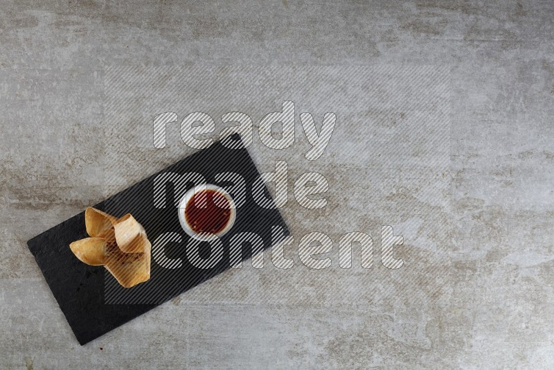 wonton cups with soy sauce ramkin on rectangle slate on grey textured counter top