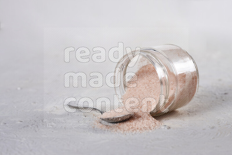 A glass jar full of fine himalayan salt on white background
