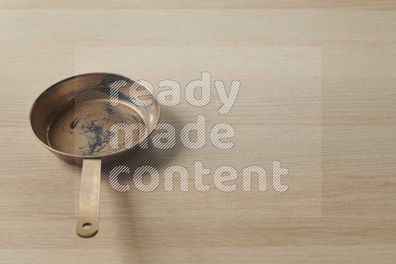 A small copper pan on light wooden background
