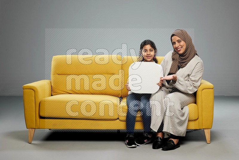 Mom and daughter sitting holding social media sign on gray background