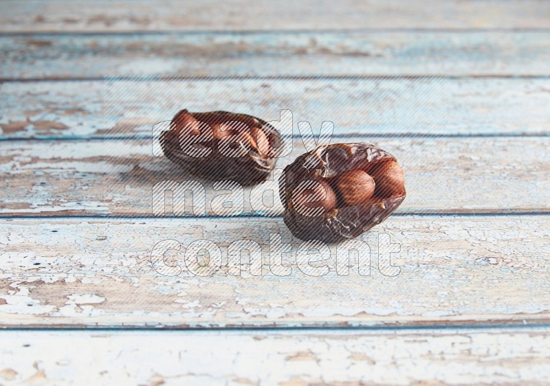 two hazelnuts stuffed madjoul dates on a light blue wooden background