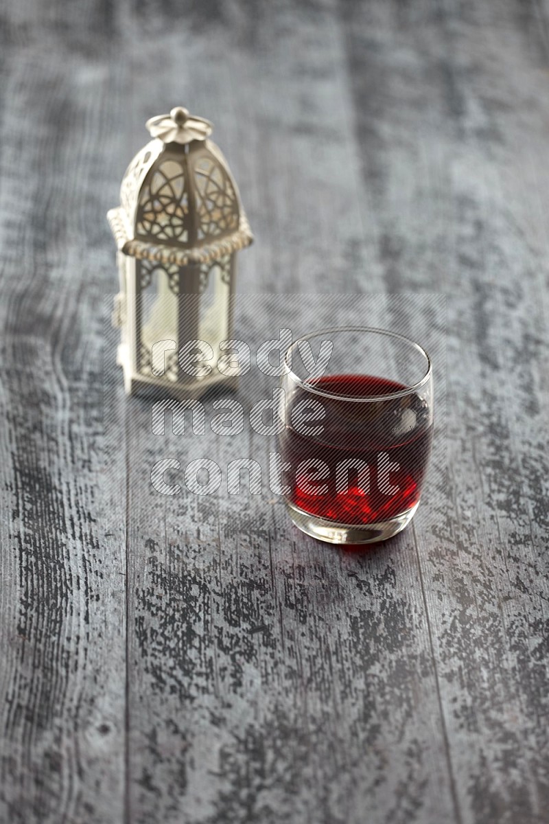 A white lantern with drinks, dates, nuts, prayer beads and quran on grey wooden background