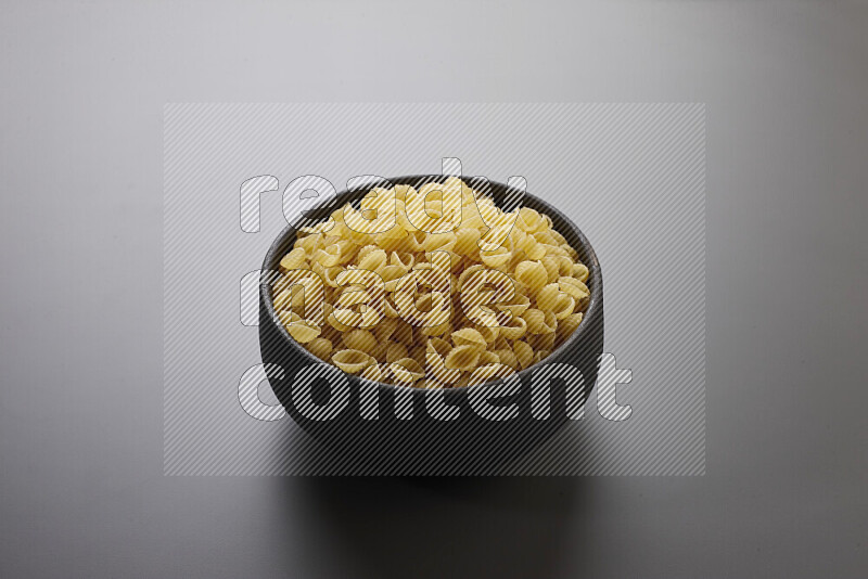Shells pasta in a pottery bowl on grey background