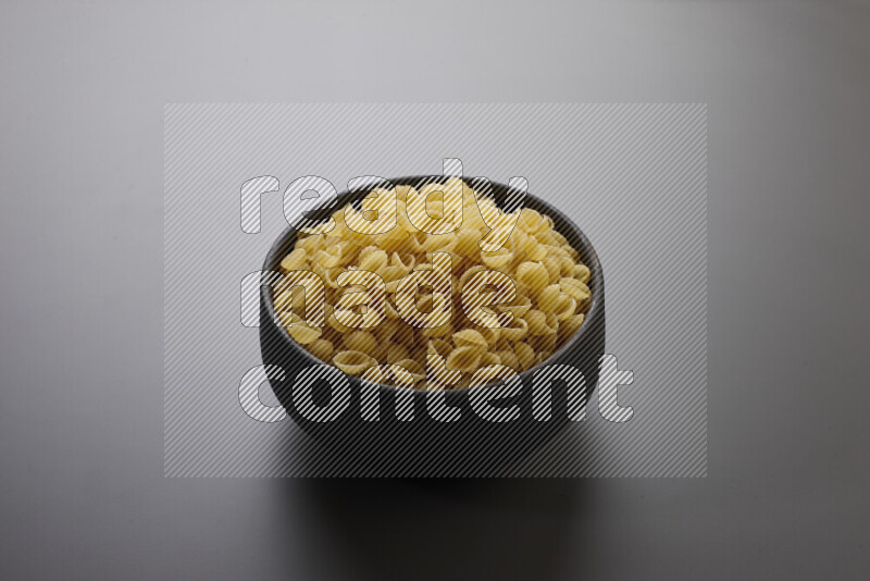 Shells pasta in a pottery bowl on grey background