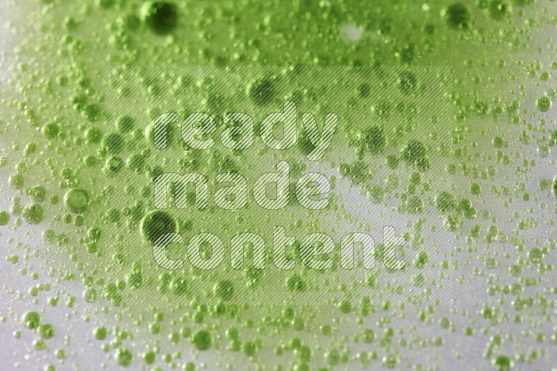 Close-ups of abstract green watercolor drops on oil Surface on white background