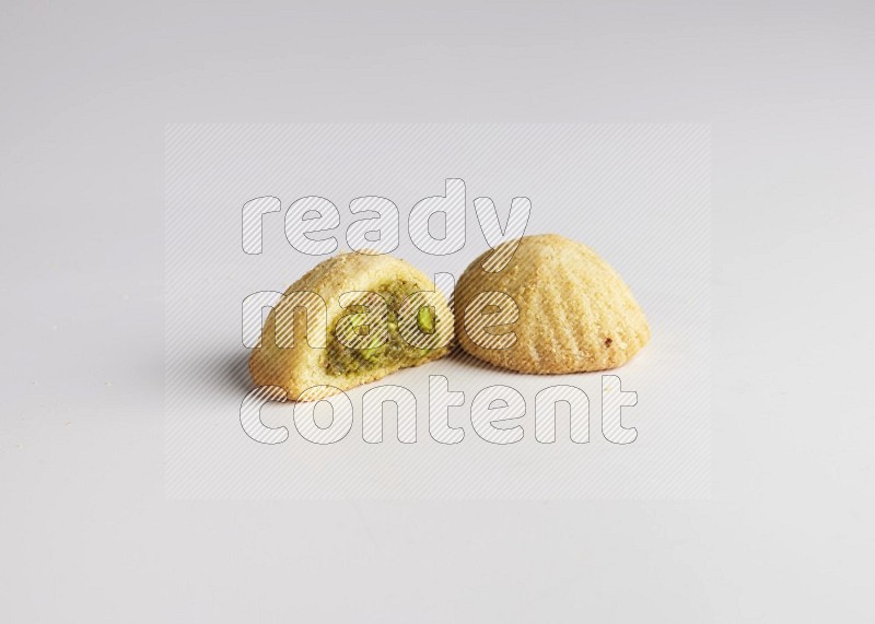 Two Pieces of Maamoul filled with pistachio paste  one of them is cut direct on white background