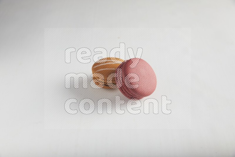 45º Shot of of two assorted Brown Irish Cream, and Red Velvet macarons on white background