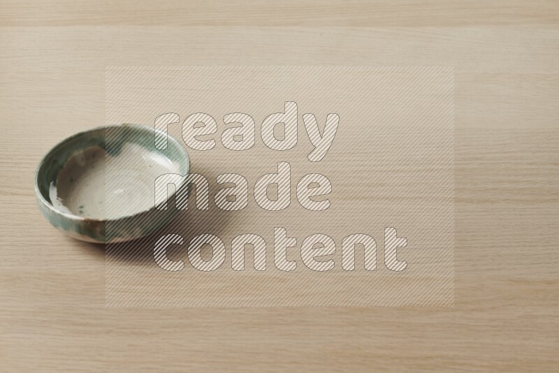 A multicolored pottery bowl on light wooden background